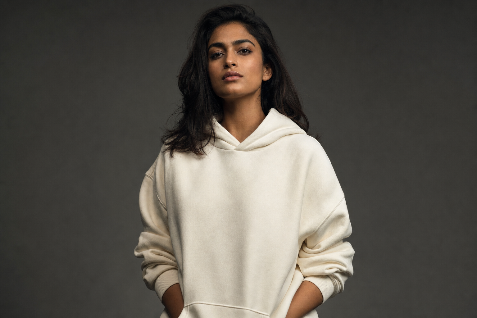 Woman wearing an oversized ivory Kosha hoodie, studio portrait